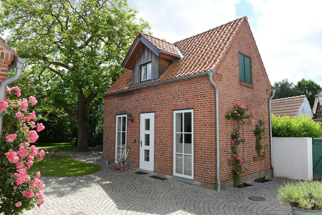 una casa di mattoni rossi con porte bianche e fiori di Räucherhäuschen a Fehmarn