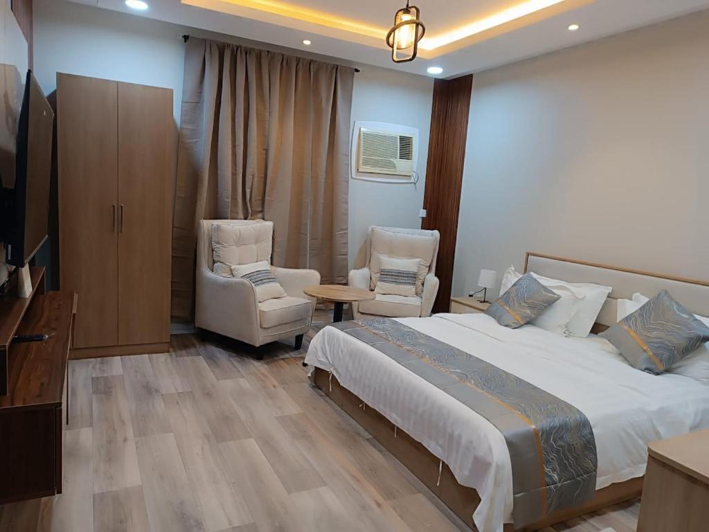 ein Schlafzimmer mit einem Bett und zwei Stühlen und einem Fernseher in der Unterkunft روف جازان ذات التصميم الفندقي in Dschāzān