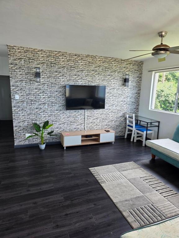 ein Wohnzimmer mit einem TV an einer Backsteinwand in der Unterkunft 92 Camarque - 3 Bedroom Apartment In Umdloti - 180 Degree Sea Views in Umdloti
