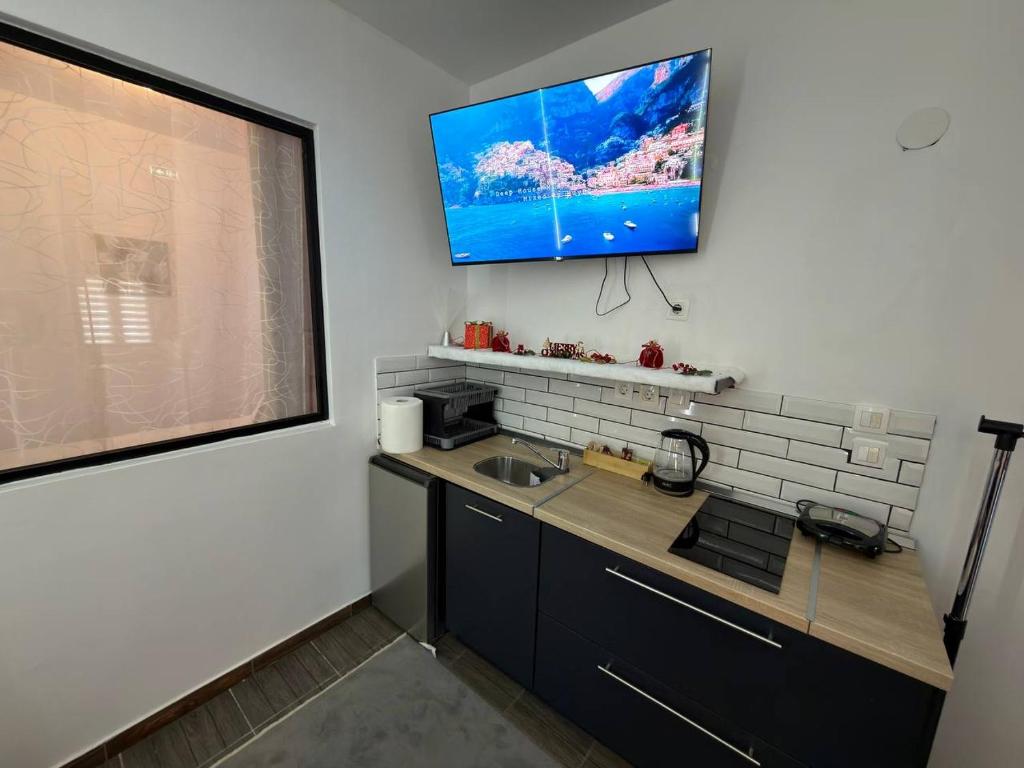 eine Küche mit einem Waschbecken und einem TV an der Wand in der Unterkunft Qulity Hayati Alexandroupolis in Alexandroupoli