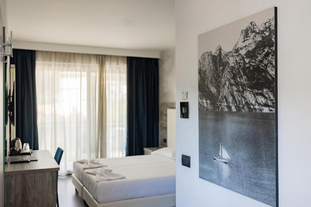 a bedroom with a bed and a picture of a boat at Hotel De Nac in Nago-Torbole