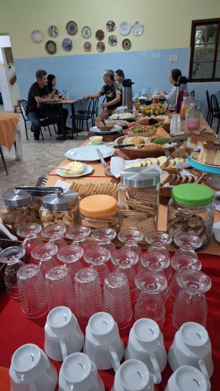 a long table filled with glasses and plates of food at Pousada do Nilo in Itapemirim