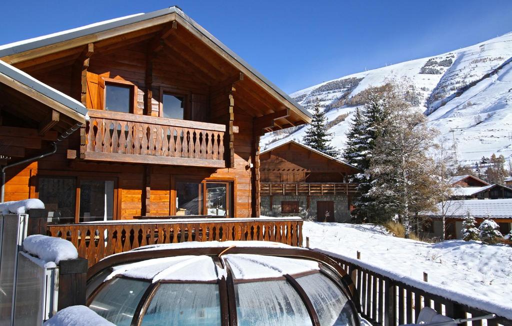 a log cabin with a car parked in the snow at Odalys Chalet le Soleil Levant in Les Deux Alpes