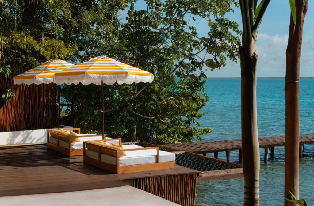 two umbrellas sitting on a wooden deck with the ocean at Mikasa Bacalar Hotel Boutique, Lagoon Front in Bacalar