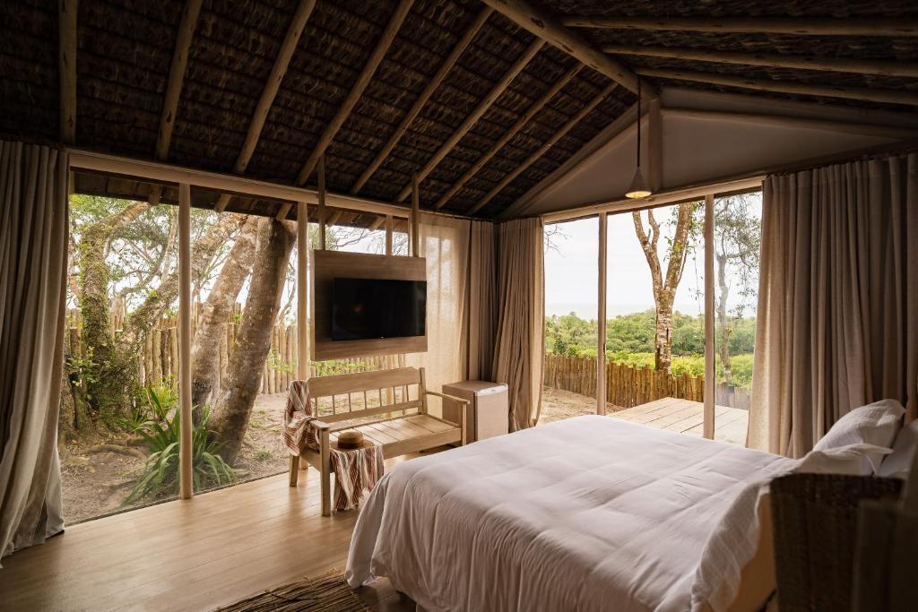 een slaapkamer met een bed en een groot raam bij Bela Vista Hotel Boutique in Caraíva