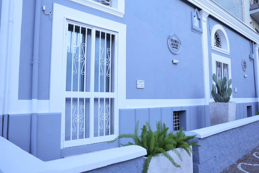 ein blau-weißes Gebäude mit einer Tür in der Unterkunft Flora House Pompei Scafati in Scafati