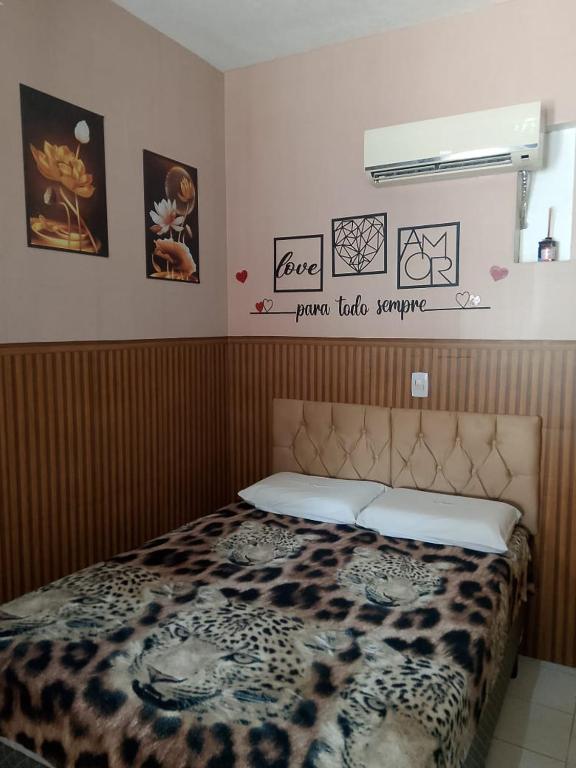 a bed in a bedroom with pictures on the wall at Aracaju Suite - Wi-Fi, Ar e Ótima Localização in Aracaju