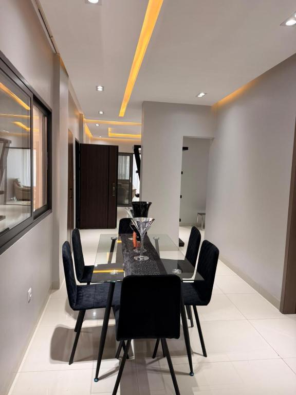 una sala da pranzo con tavolo in vetro e sedie nere di Libellule a Dakar