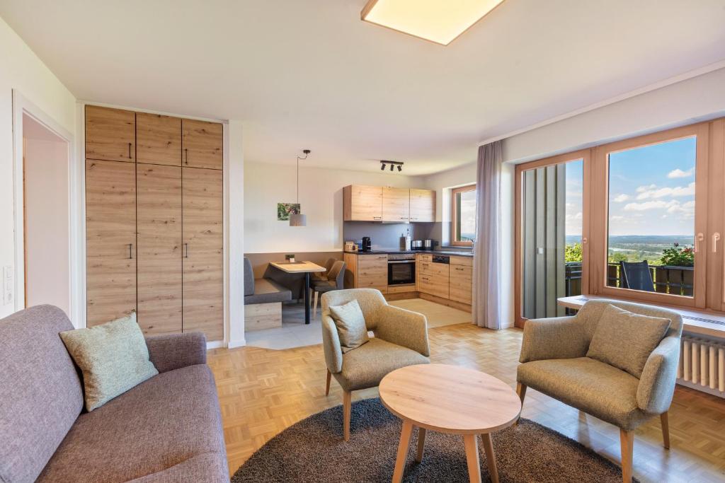 a living room with a couch and chairs and a kitchen at PAPPELHOF Landurlaub mit Panoramablick - Motorradunterkunft Fahrradunterkunft in Bad Bellingen
