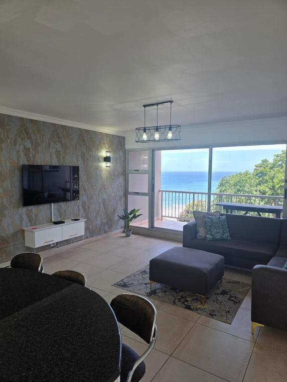 ein Wohnzimmer mit Sofa und Fernseher in der Unterkunft 101 Camarque - 3 Bedroom Apartment In Umdloti - 180 Degree Sea Views in Umdloti