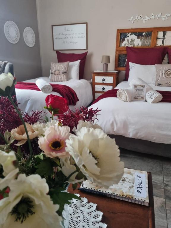 a bedroom with two beds and a table with flowers at Grace Guesthouse in Potchefstroom