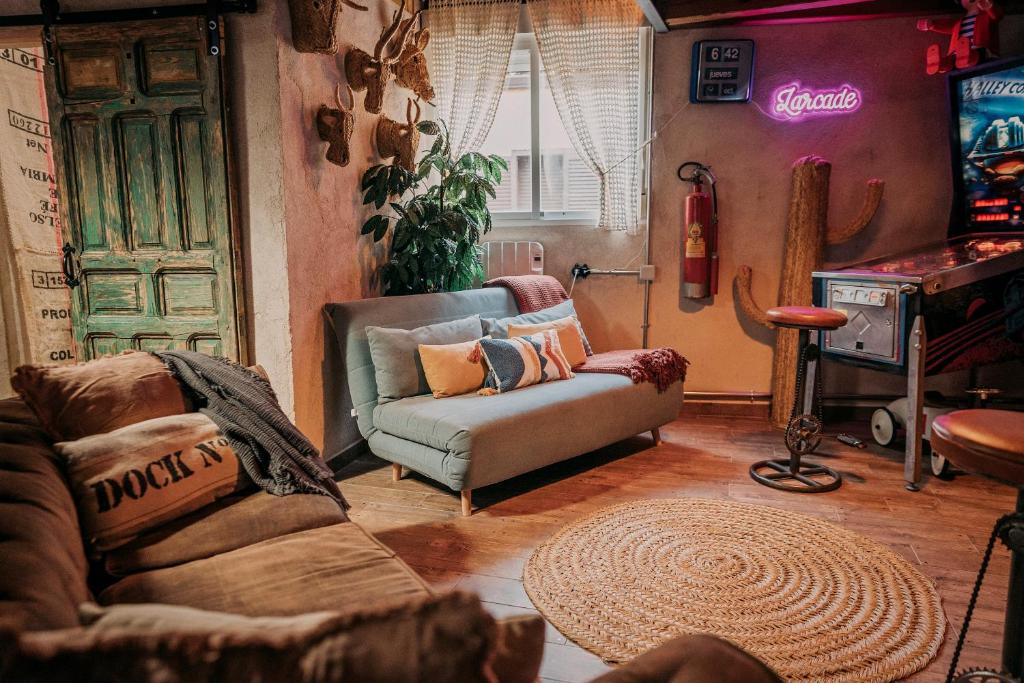 un soggiorno con un divano e una stanza con un videogioco di LARCADE Loft Industrial a Castillo de Bayuela