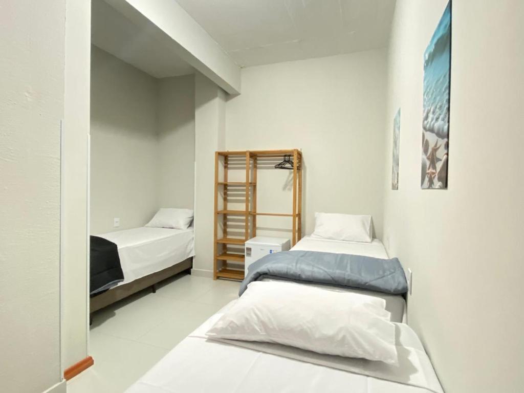 a bedroom with two beds and a mirror at Pousada Âncora in Gravataí