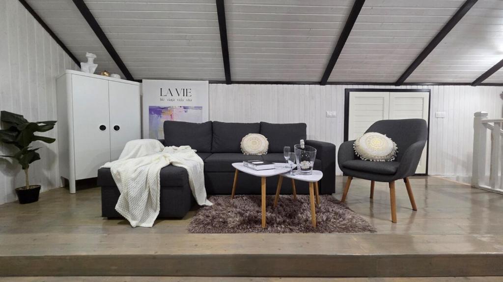 un soggiorno con divano nero e 2 sedie di The HIDE - Loftette a Ploieşti