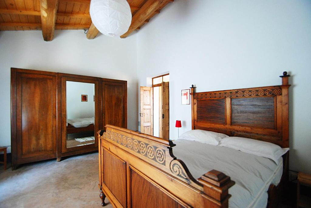 een slaapkamer met een groot houten bed en een spiegel bij Asino Nero in Milis