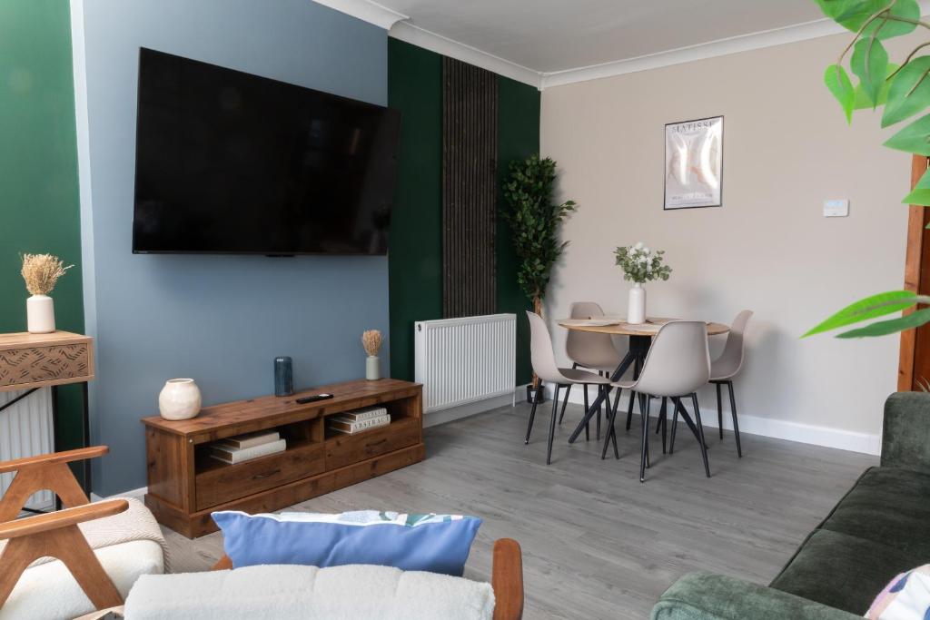 een woonkamer met een tv en een tafel bij Vacant Nests Ivy Cottage 3BR Wi-Fi in Banton