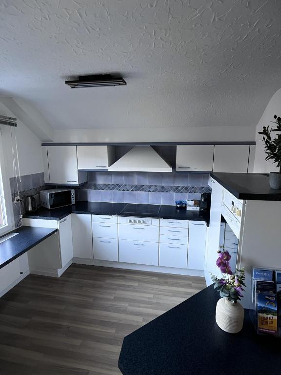 a kitchen with white cabinets and a black counter top at Apartment Spiez - Lake view - for 7 guests in Thun