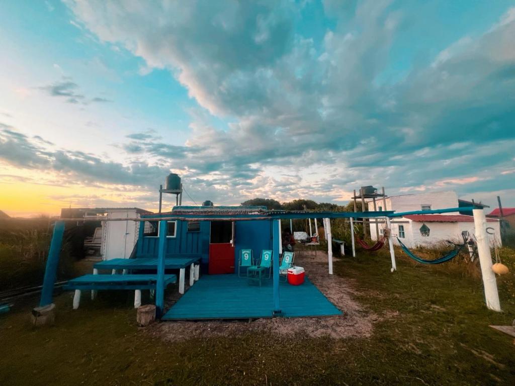 een klein huis met een speeltuin in een veld bij El Antiguo Hostel in Cabo Polonio