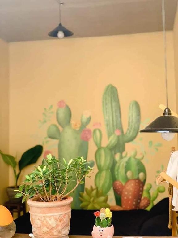 a wall with a painting of cactuses on it at Homestay GÁC MƠ Vũng Tàu in Vung Tau