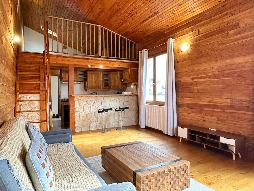 een woonkamer met een bank en een tafel bij Duplex Chalet style private yard 150m to RER in Bagneux