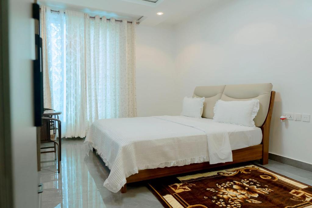 a white bedroom with a bed and a window at Dorlan Hotel in Kigali