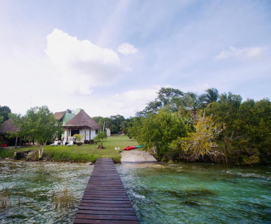 een houten brug over een rivier voor een huis bij Luigi’s Glamping in Bacalar