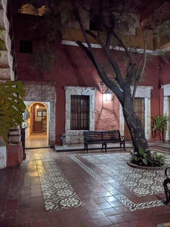 an empty courtyard with a bench and a tree at La Casa de Melgar in Arequipa