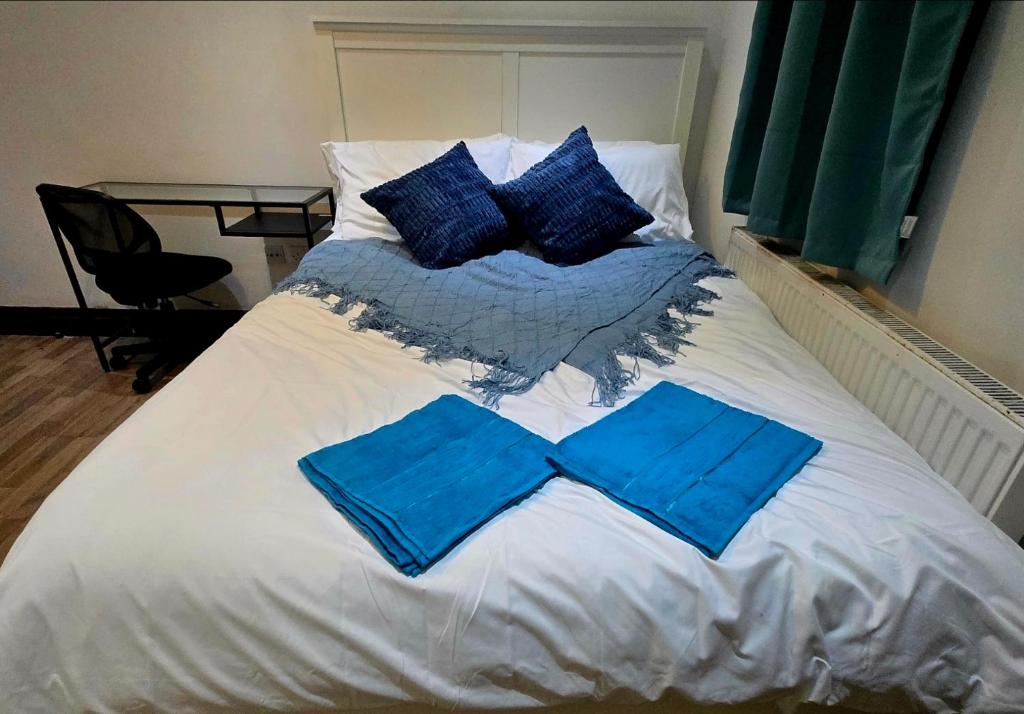 een bed met blauwe lakens en kussens erop bij Stratford Guest House in Londen