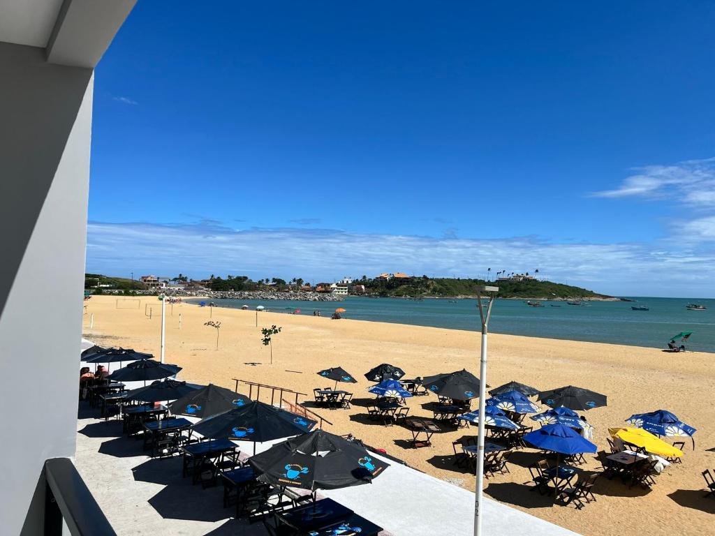 a beach with a bunch of chairs and umbrellas at Pé na Areia in Guarapari
