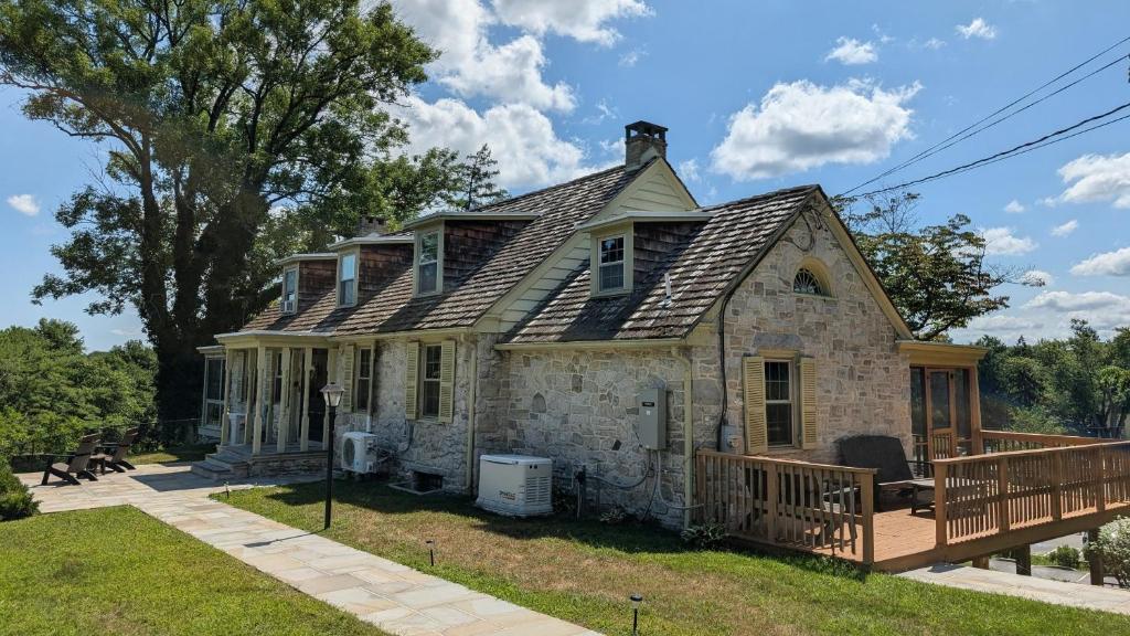 an old stone house with a porch and a deck at Downingtown Manor - 1900s Farmhouse with Creek Views in Downingtown