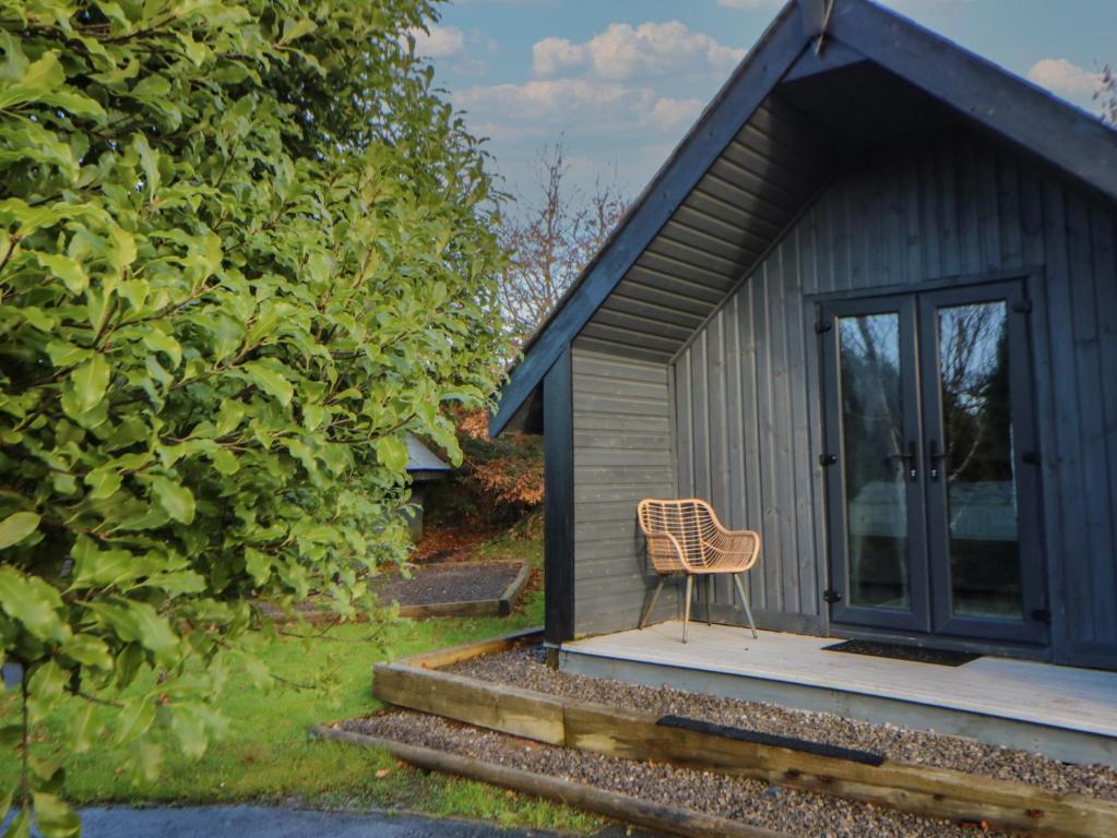 a chair sitting on the porch of a tiny house at Glamping Tri Pod 7 - Gower in Swansea