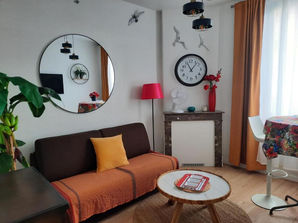 ein Wohnzimmer mit einer Couch und einem Spiegel in der Unterkunft LA GRANV'ILLAISE in Granville