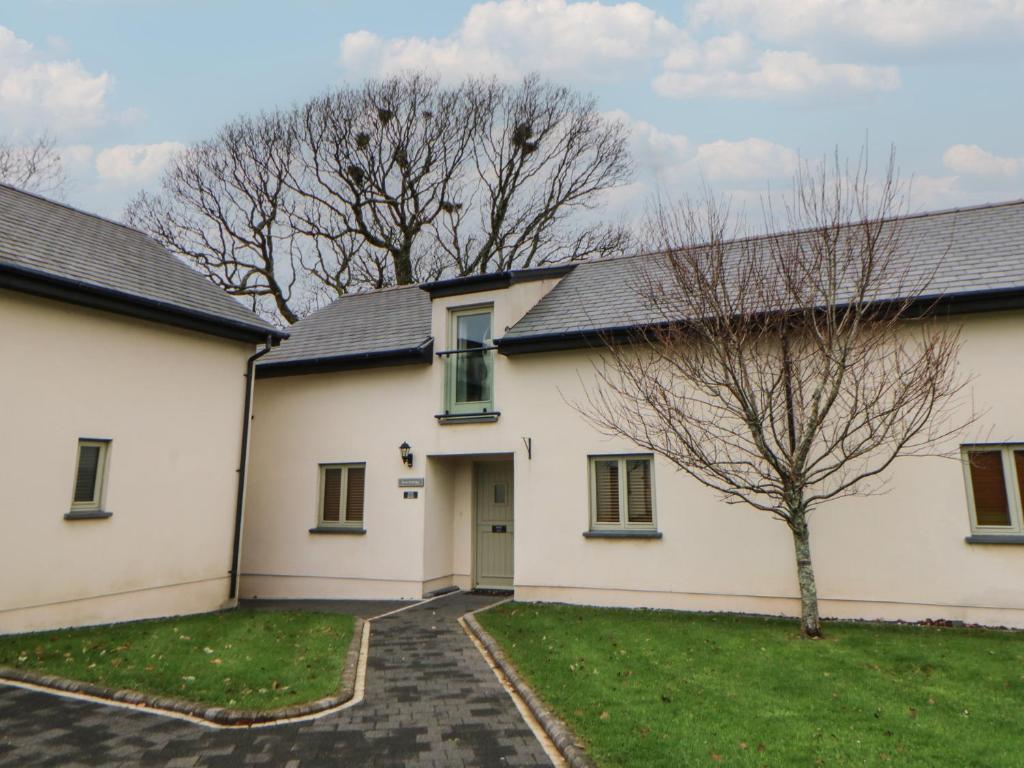 a white house with a tree in the yard at Rose Apartment - Gower in Swansea