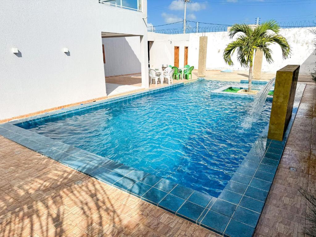 a swimming pool with a blue tiled floor and a house at Eficiência - Casa Recanto dos Ventos - Casa grande para lazer entre família e amigos in Camocim