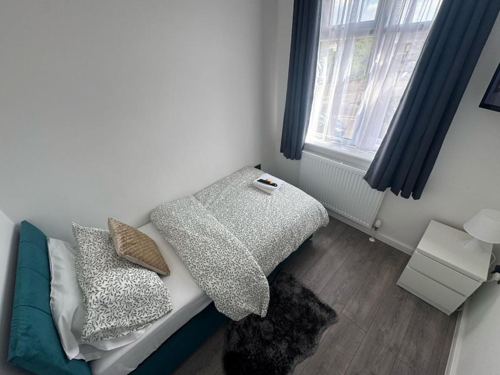 Cette chambre comprend un lit avec des oreillers et une fenêtre. dans l'établissement BXH B4 Cozy single room Bexleyheath, à Bexleyheath