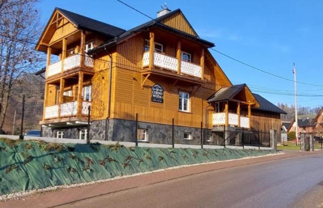 une grande maison en bois sur le côté d'une rue dans l'établissement Corno Woda Apartamenty, à Jaworki