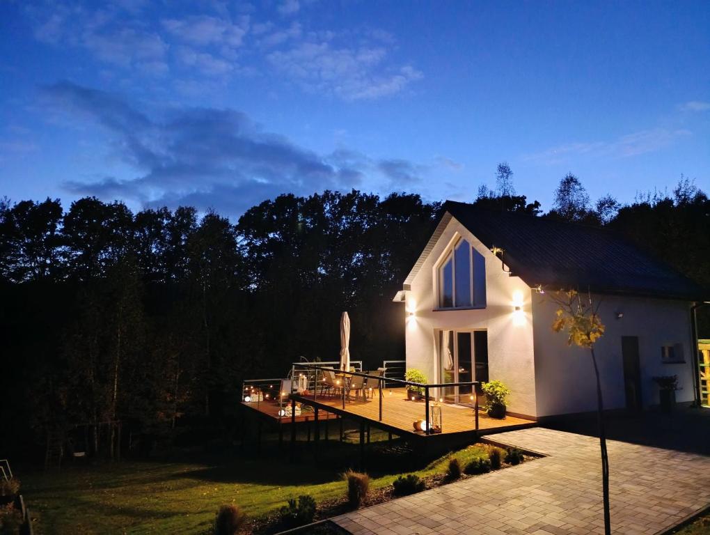 een klein wit huis met een terras 's nachts bij Domek Na Wądołach in Jedlicze