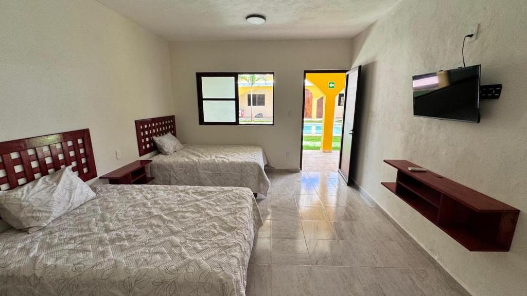 een slaapkamer met twee bedden en een flatscreen-tv bij Hotel Villa Chucum in Tikuch