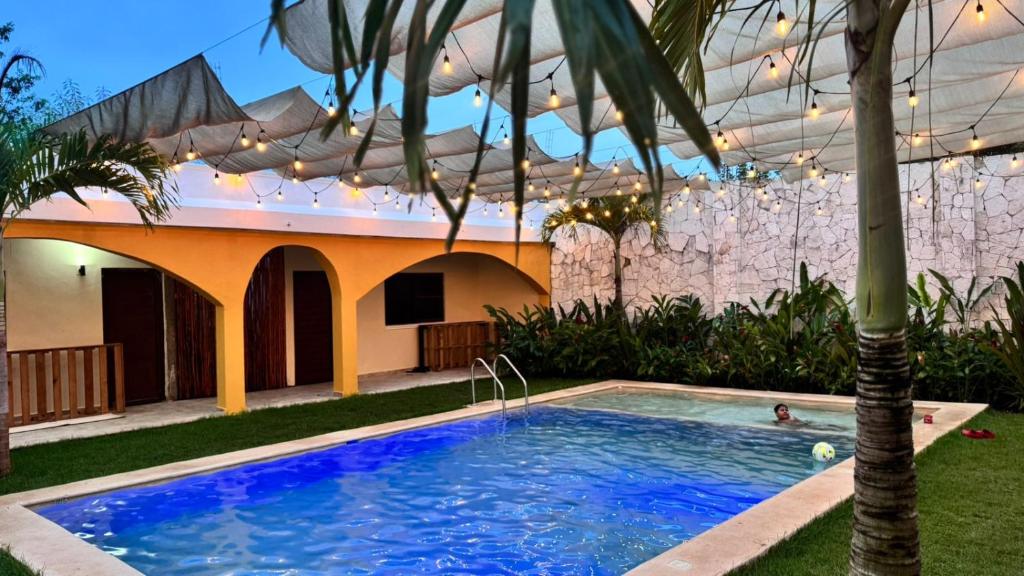 a swimming pool in front of a house with a palm tree at Hotel Villa Chucum-Tikuch in Tikuch
