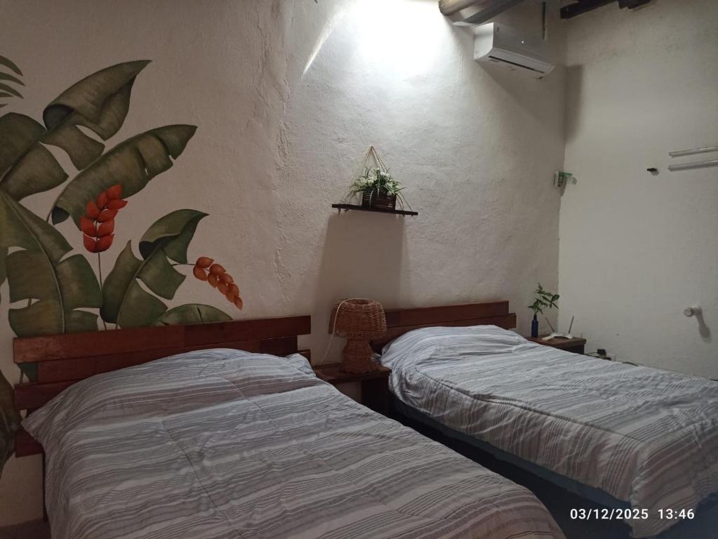 twee bedden in een slaapkamer met een muurschildering aan de muur bij Casa Guacamaya in Izamal