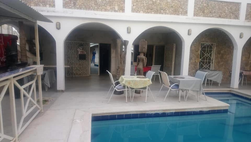 een huis met een zwembad en een tafel en stoelen bij Villa Romaine in Toubab Dialaw