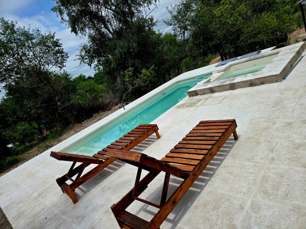 eine Holzbank am Rand eines Schwimmbeckens in der Unterkunft ALTOS DE PUNILLA in Casa Grande