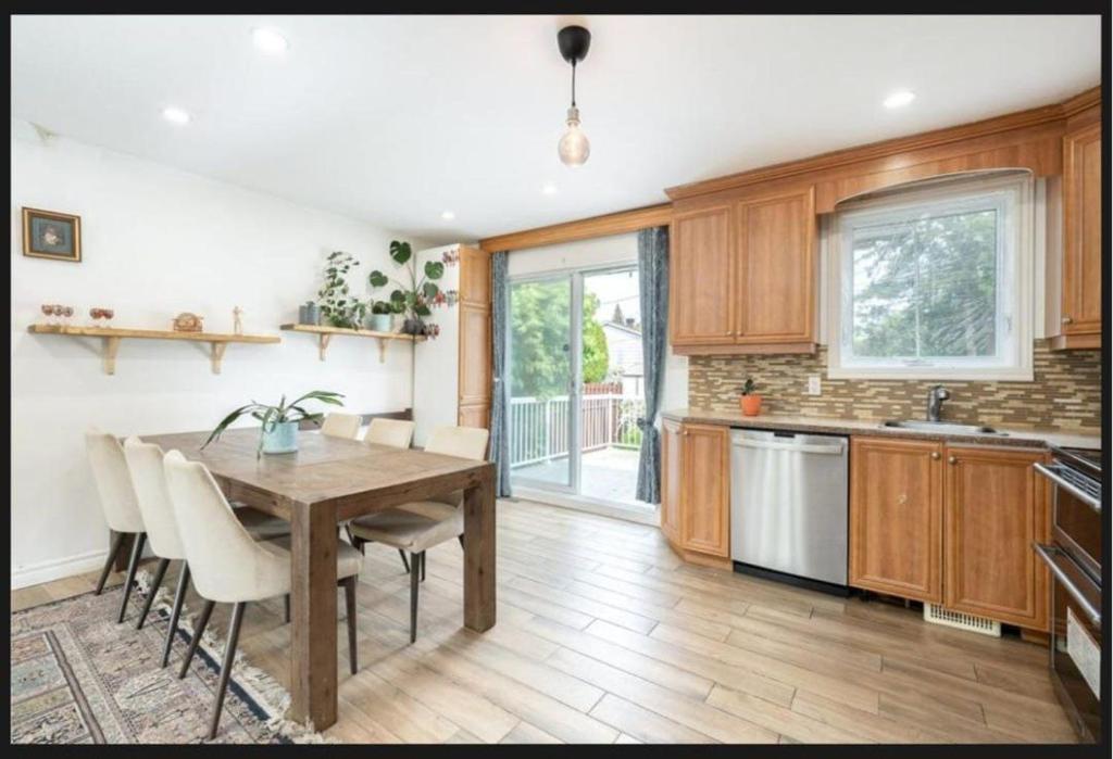 a kitchen with a wooden table and white chairs at Private Bed Room in a Beautiful Family House in Brossard