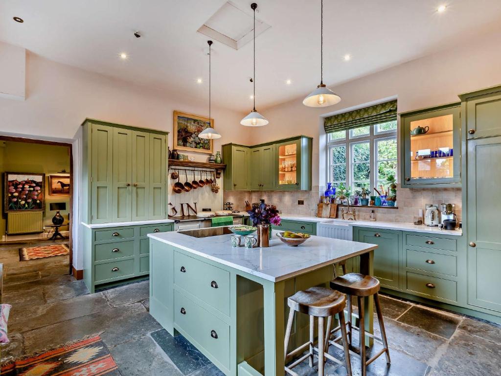 een keuken met groene kasten en een kookeiland bij 5 Bed in Fitzhead 95570 in Fitzhead