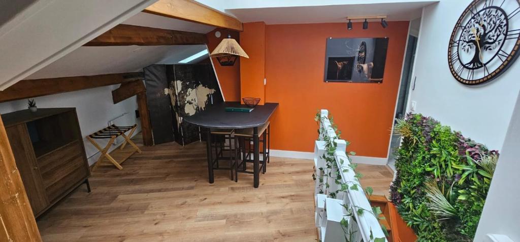 een woonkamer met een tafel en een klok aan de muur bij Cozy Loft sous les toits in Le Kremlin-Bicêtre