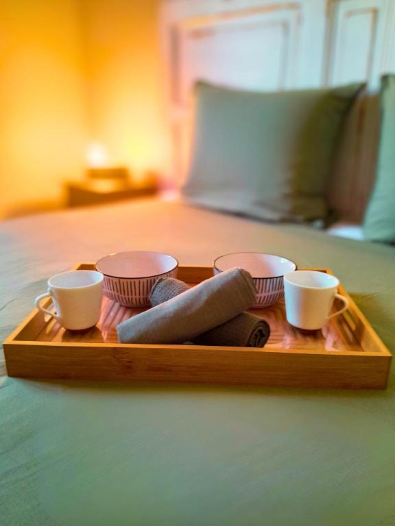 a tray with three cups and socks on a bed at La Case Auvergnate in Anse-Bertrand