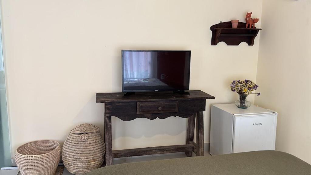 un soggiorno con TV su un tavolo di Suite completa com área verde a Camaçari