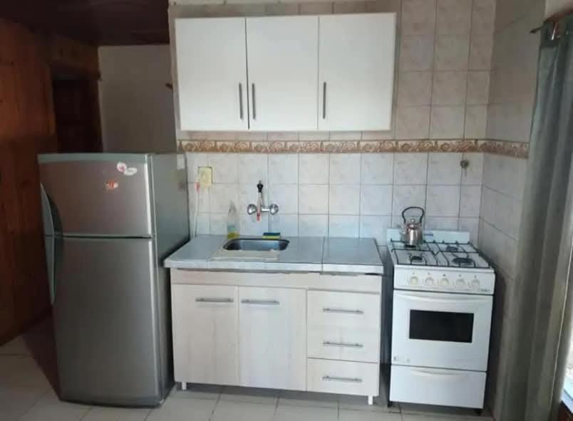 a kitchen with a stove and a sink and a refrigerator at Deptos Eliana in El Bolsón