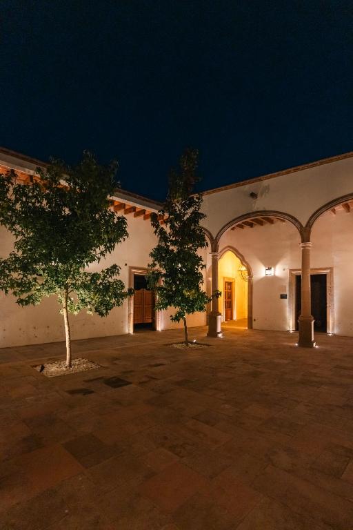 two trees in the courtyard of a building at night at Hotel Agua de Plata in San Luis Potosí