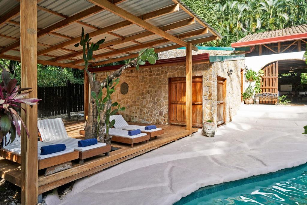 eine Terrasse mit einem Pool und einer hölzernen Pergola in der Unterkunft Villa Havana in Mal País